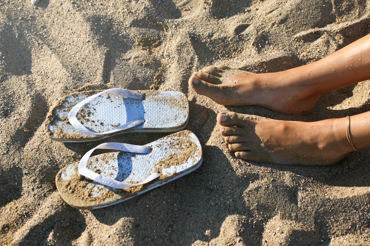 Bare feet on beach with flip flops