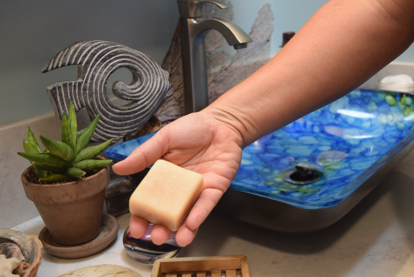 Hand holding Apothecuryous soap at bathroom sink