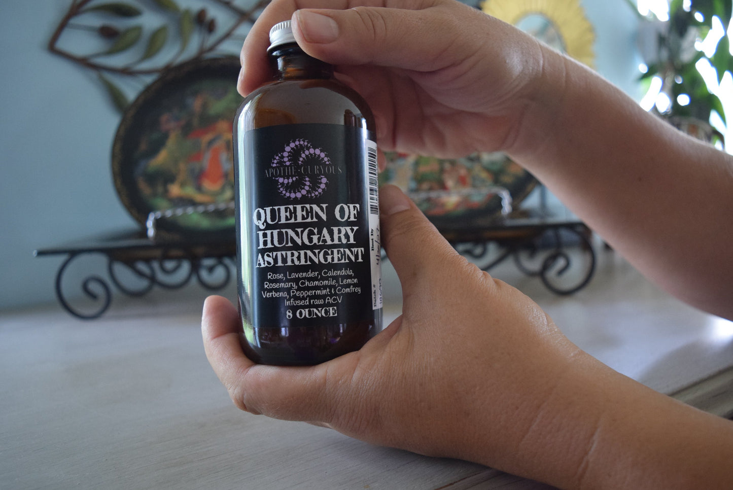 Hands holding 8 ounce amber glass jar of Queen of Hungary astringent, Apothecuryous