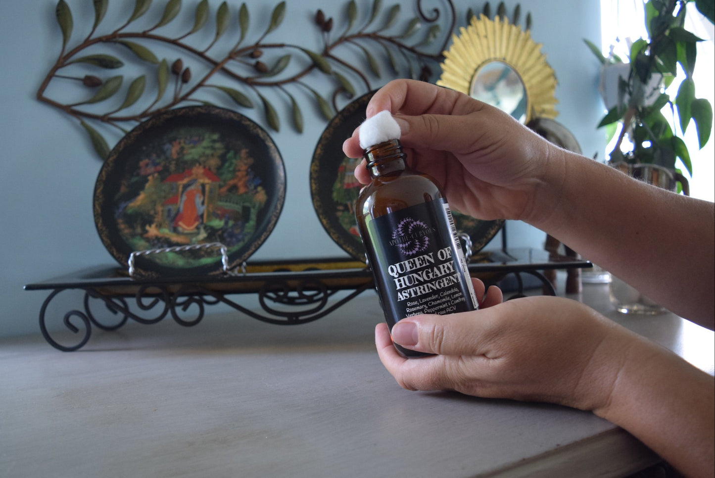 Amber glass jar of astringent being applied to cotton ball, Apothecuryous