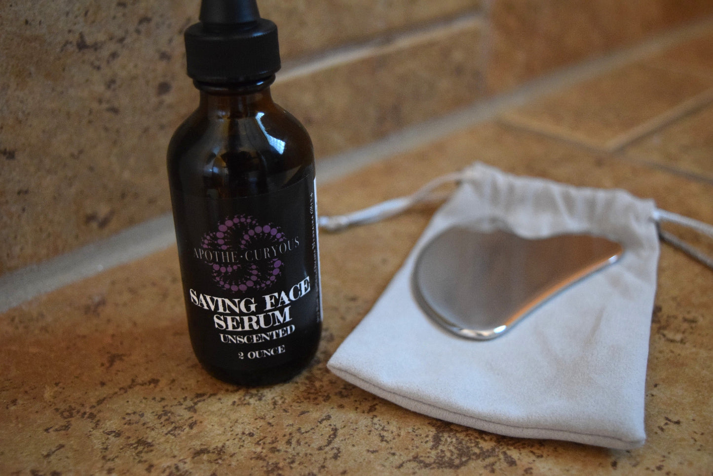 Saving Face serum in amber glass bottle with dropper top and Guasha tool with storage bag