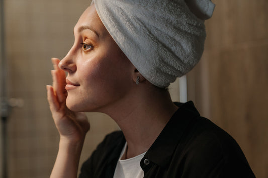 Profile of woman looking in mirror touching her face