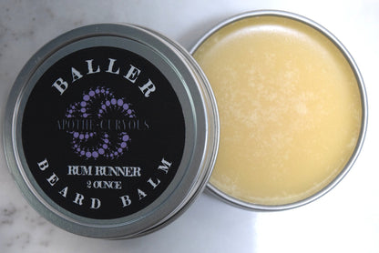Baller beard balm in aluminum tin with the lid off. Rich golden balm color, Rum Runner scent, Apothecuryous