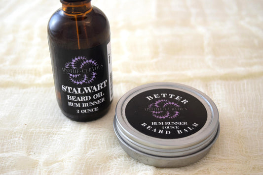 A beard care set including a bottle labeled 'Stalwart Oil Rummer' and a tin container labeled 'Better Beard Balm'.