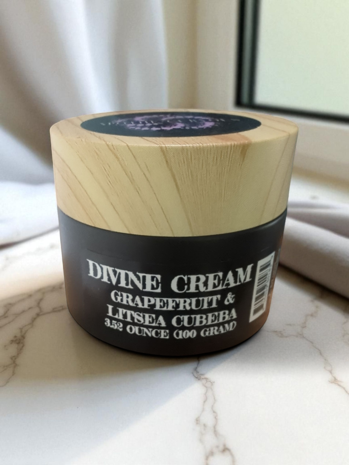 Jar of Divine Cream with grapefruit and litsea cubeba on a marble surface