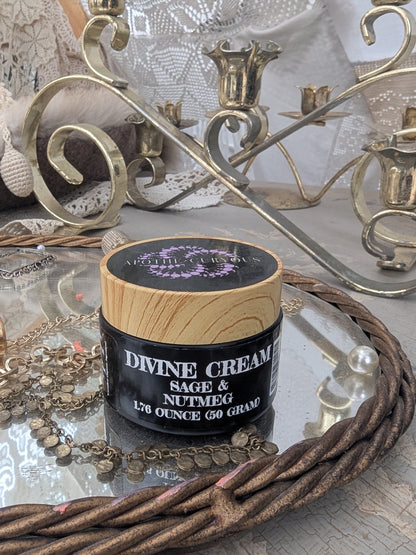 Divine cream in black glass jar on table with jewelry and mirror in background, Apothecuryous