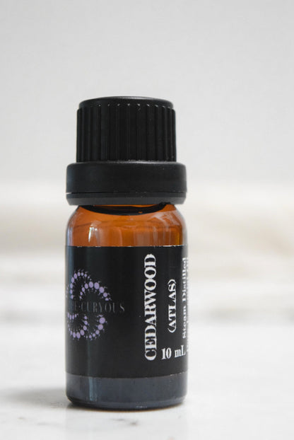 A 10 ml amber glass bottle of Cedarwood (Atlas) essential oil with a black cap and black label, set against a clean white background.