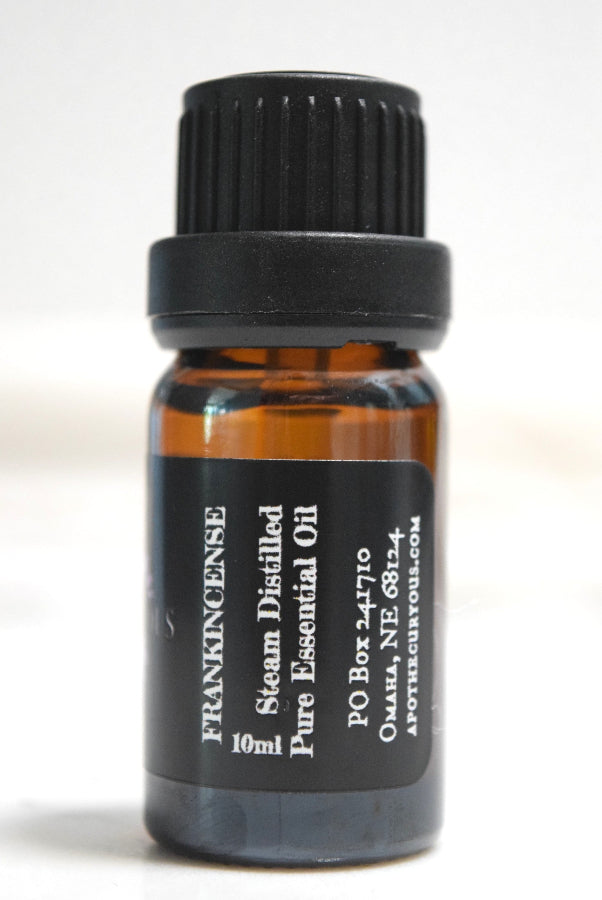 A 10ml amber glass bottle of Frankincense Steam Distilled Pure Essential Oil with a black ribbed cap and a black label, shown against a plain white background.