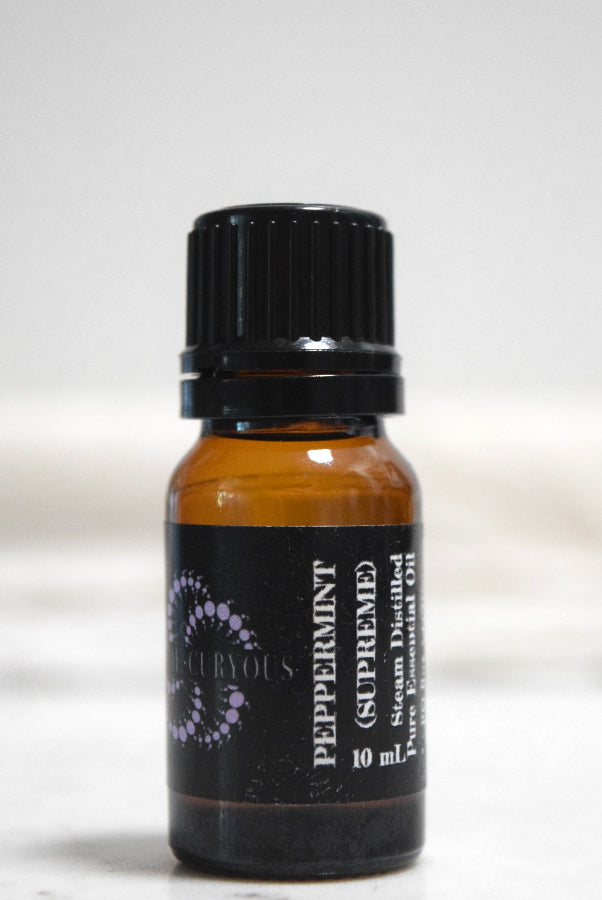 A 10 mL amber glass bottle of Peppermint (Supreme) essential oil with a black ribbed cap and black label.