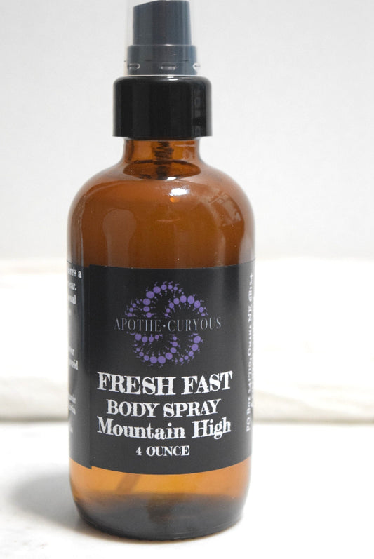 A 4-ounce amber glass body spray bottle with a black spray top and a black label reading FRESH FAST BODY SPRAY Mountain High, Apothecuryous