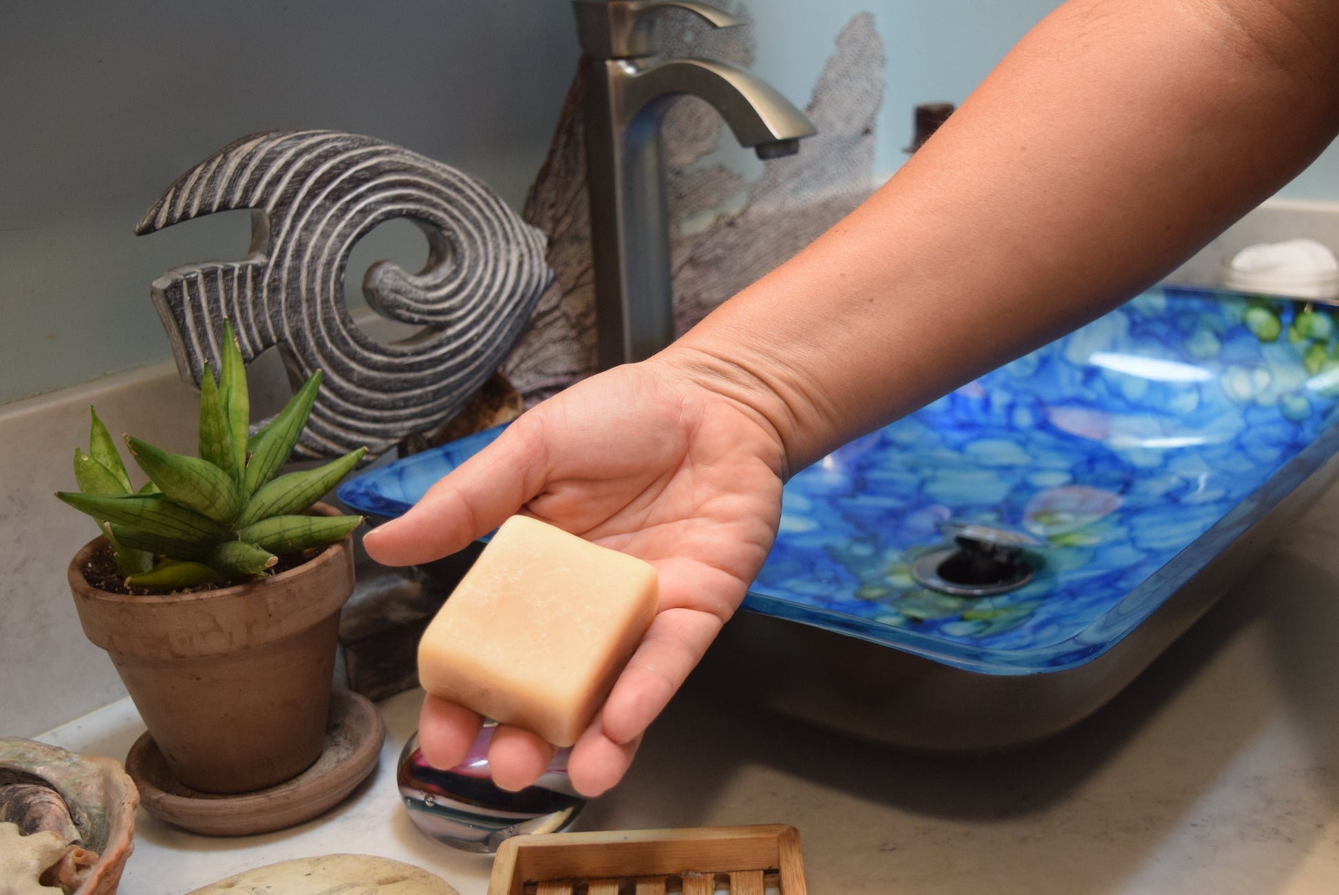 Hand holding Apothecuryous soap at bathroom sink