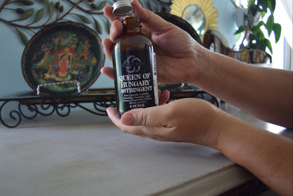 Hands holding amber glass bottle of astringent, lid off, Apothecuryous