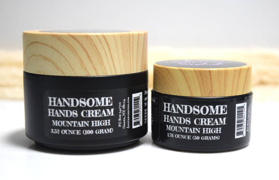 Two jars of 'Handsome Hands Cream Mountain High' with wooden lids on a light background.