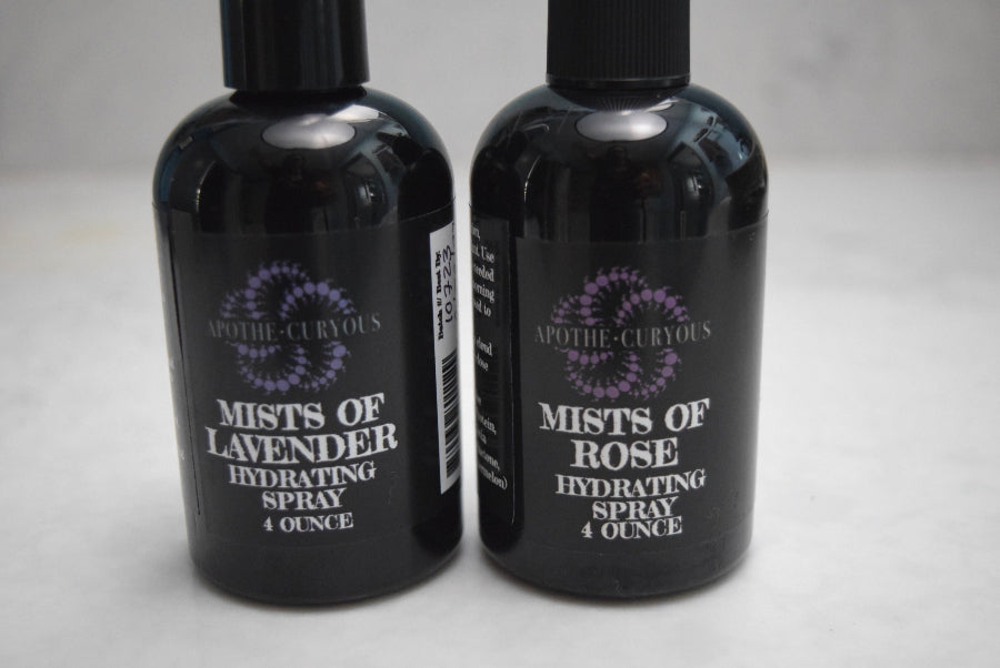 Two black spray bottles labeled 'Mists of Lavender' and 'Mists of Rose' on a light gray background.