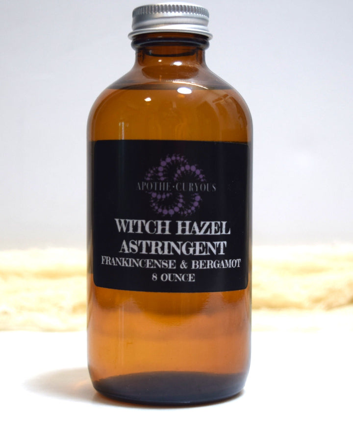 Brown glass bottle of witch hazel astringent with a label on a white background