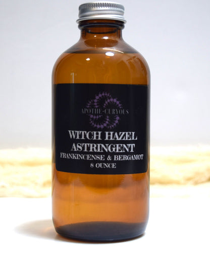 Brown glass bottle of witch hazel astringent with a label on a white background